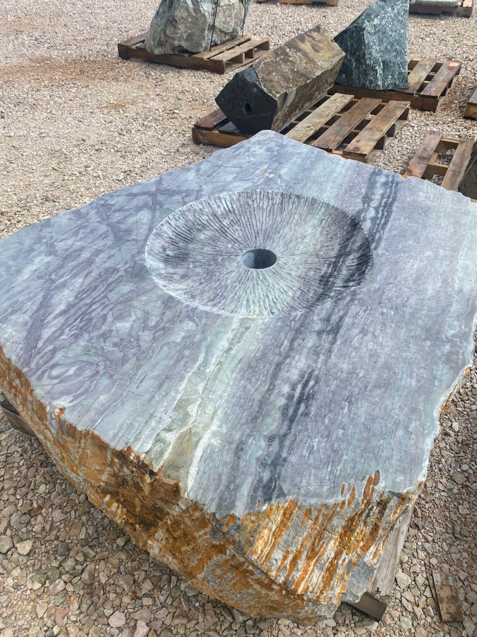 A large rock with a hole in the middle is sitting on top of a pile of gravel.