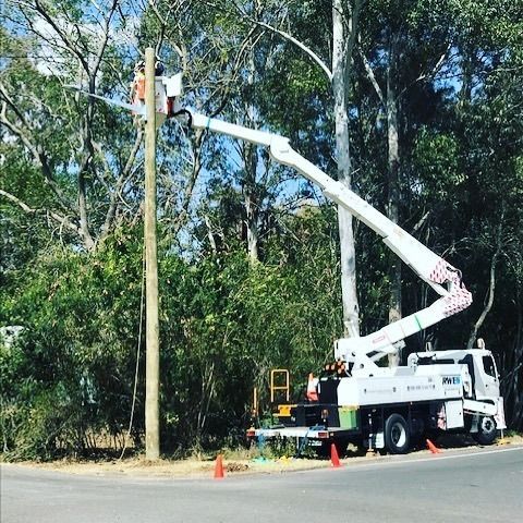 A White Truck With a Crane Attached to It is Working on a Power Pole — Rob Ward Electrical Services in West Ballina, NSW