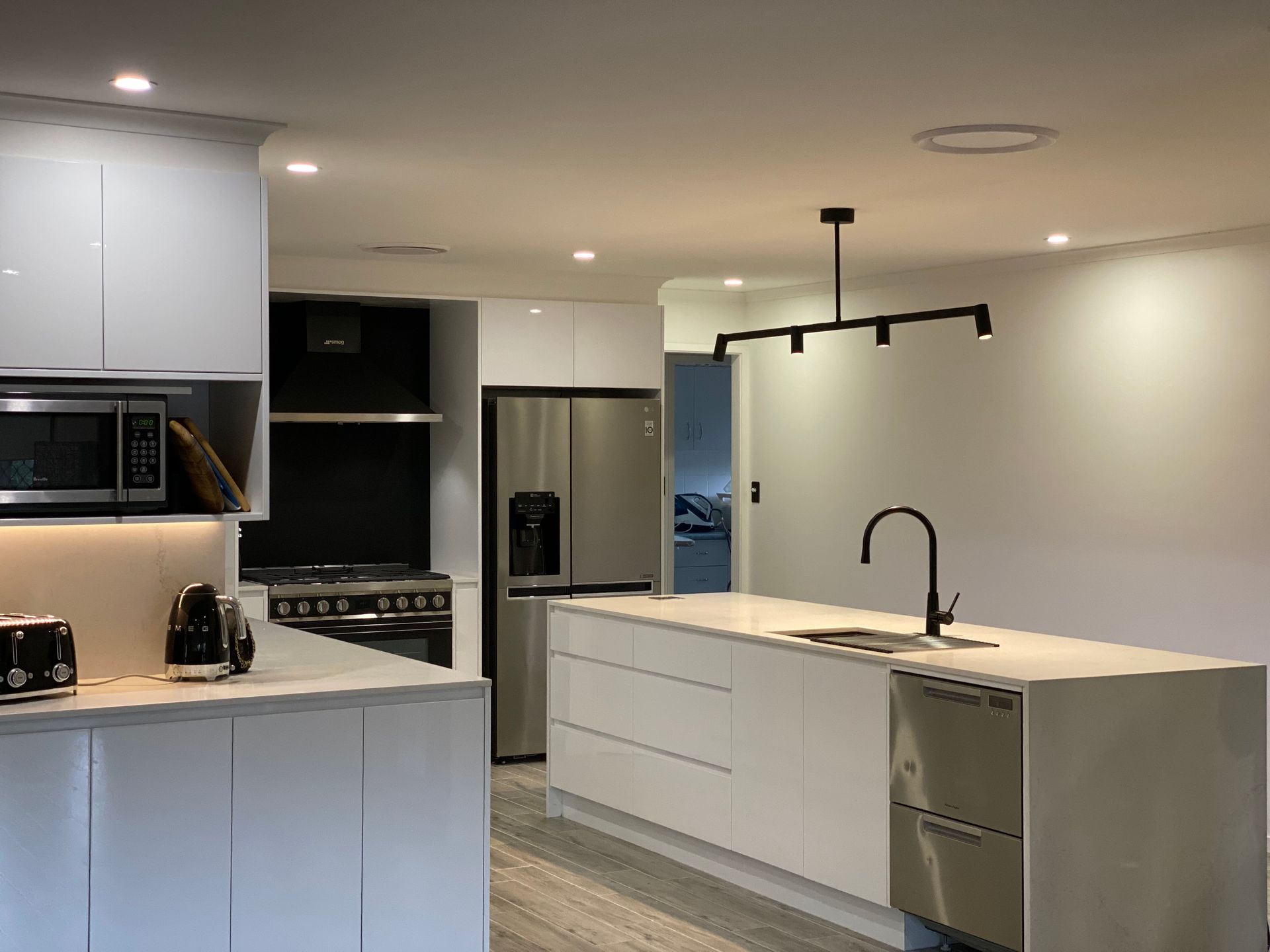 A Modern Kitchen Featuring White Cabinets, Stainless Steel Appliances — Rob Ward Electrical Services in West Ballina, NSW