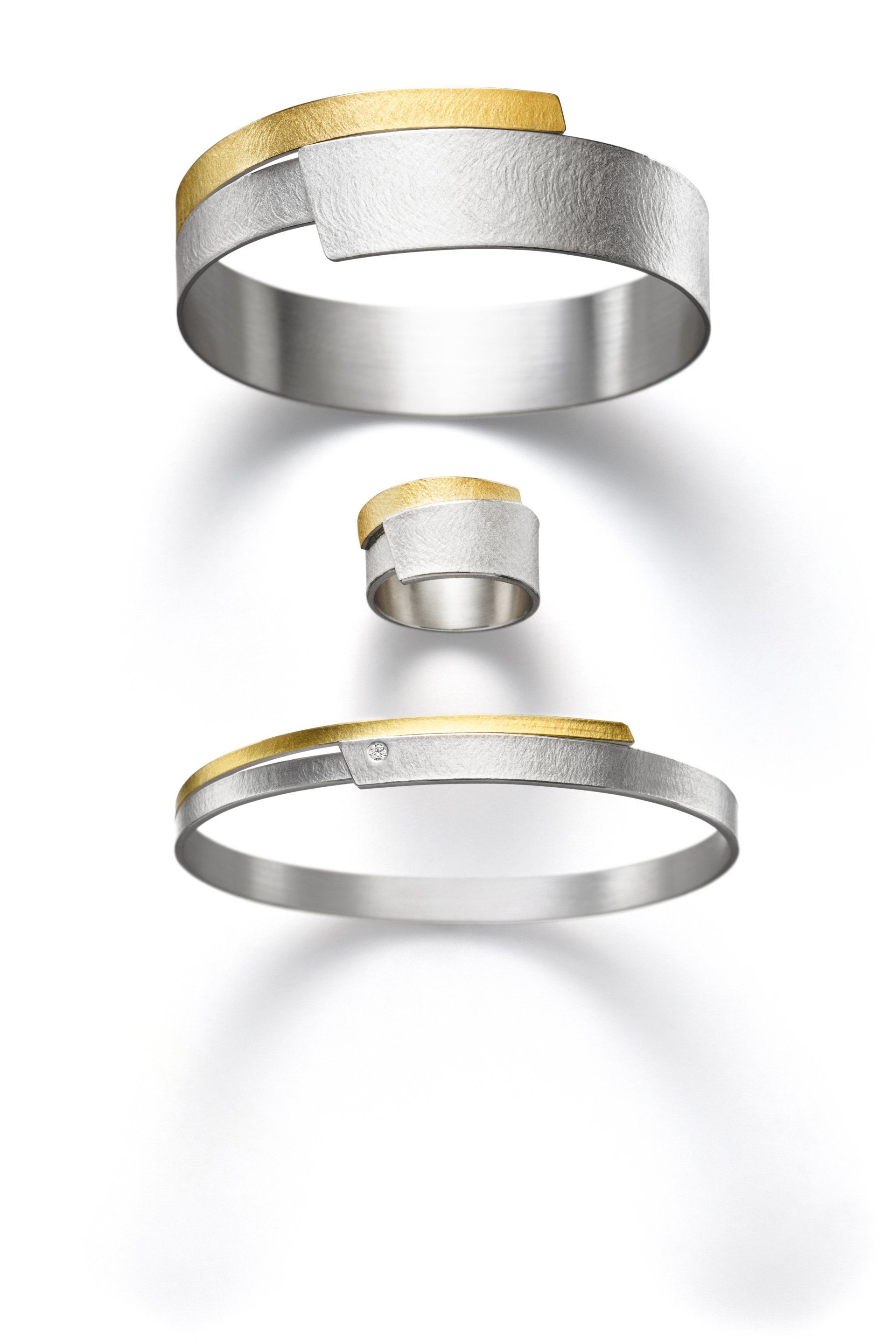 Ein silbernes und goldenes Armband und ein Ring auf weißem Hintergrund