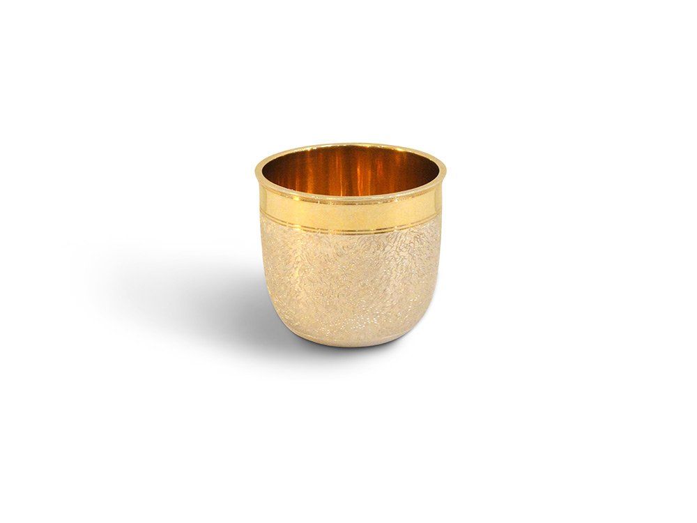 Eine kleine goldene Tasse mit goldenem Rand auf weißem Hintergrund.