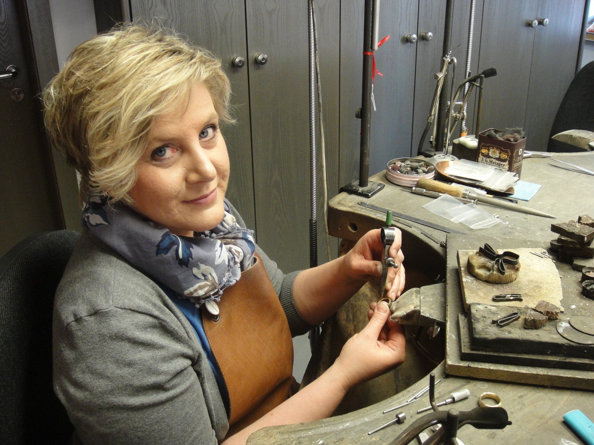 Eine Frau sitzt an einem Schreibtisch und hält ein Stück Metall