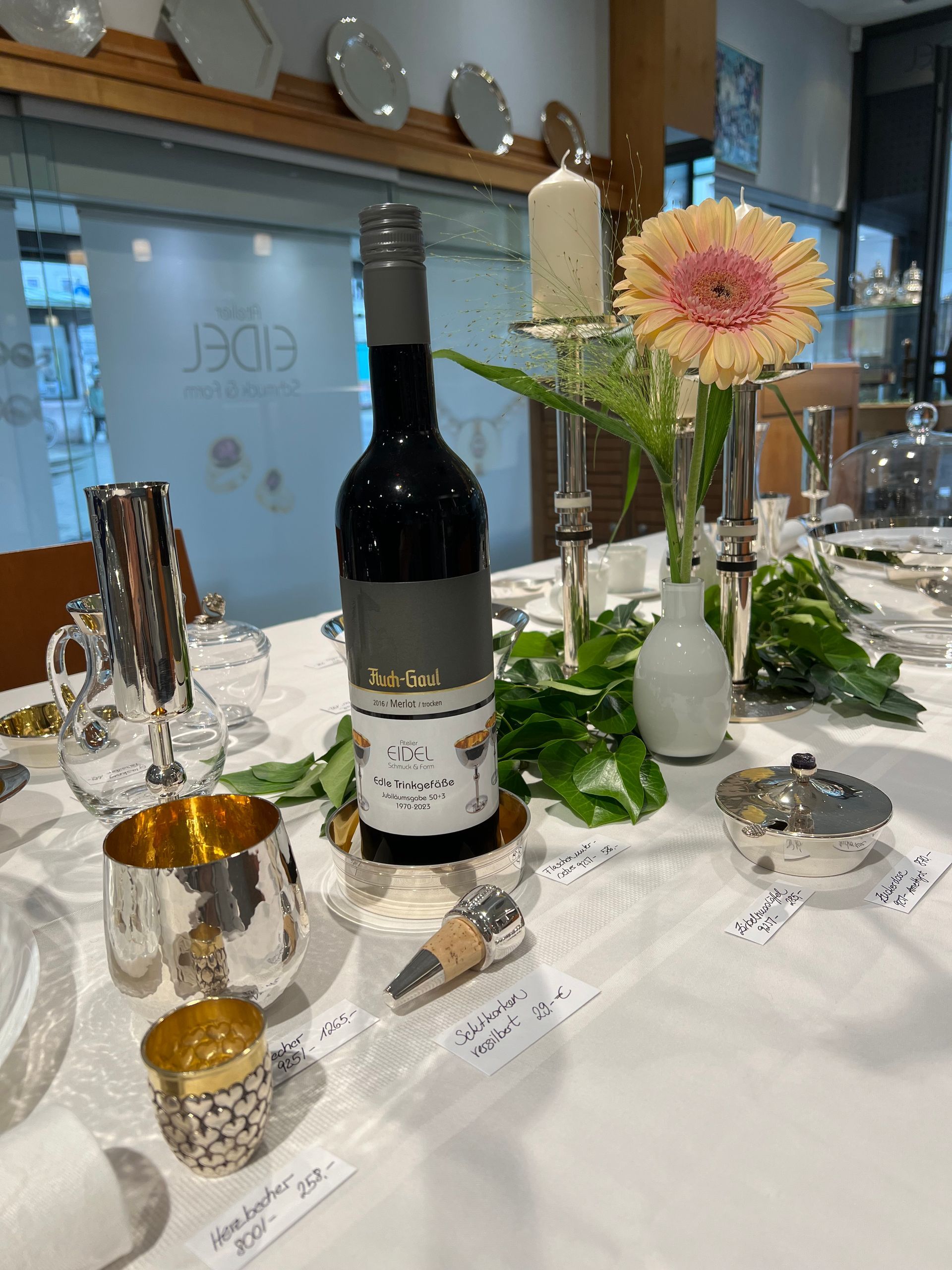 Auf einem Tisch steht eine Flasche Wein neben einer Vase mit Blumen.