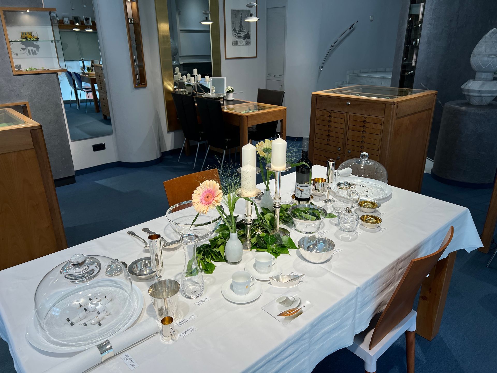 Ein langer Tisch mit einer weißen Tischdecke und Kerzen darauf