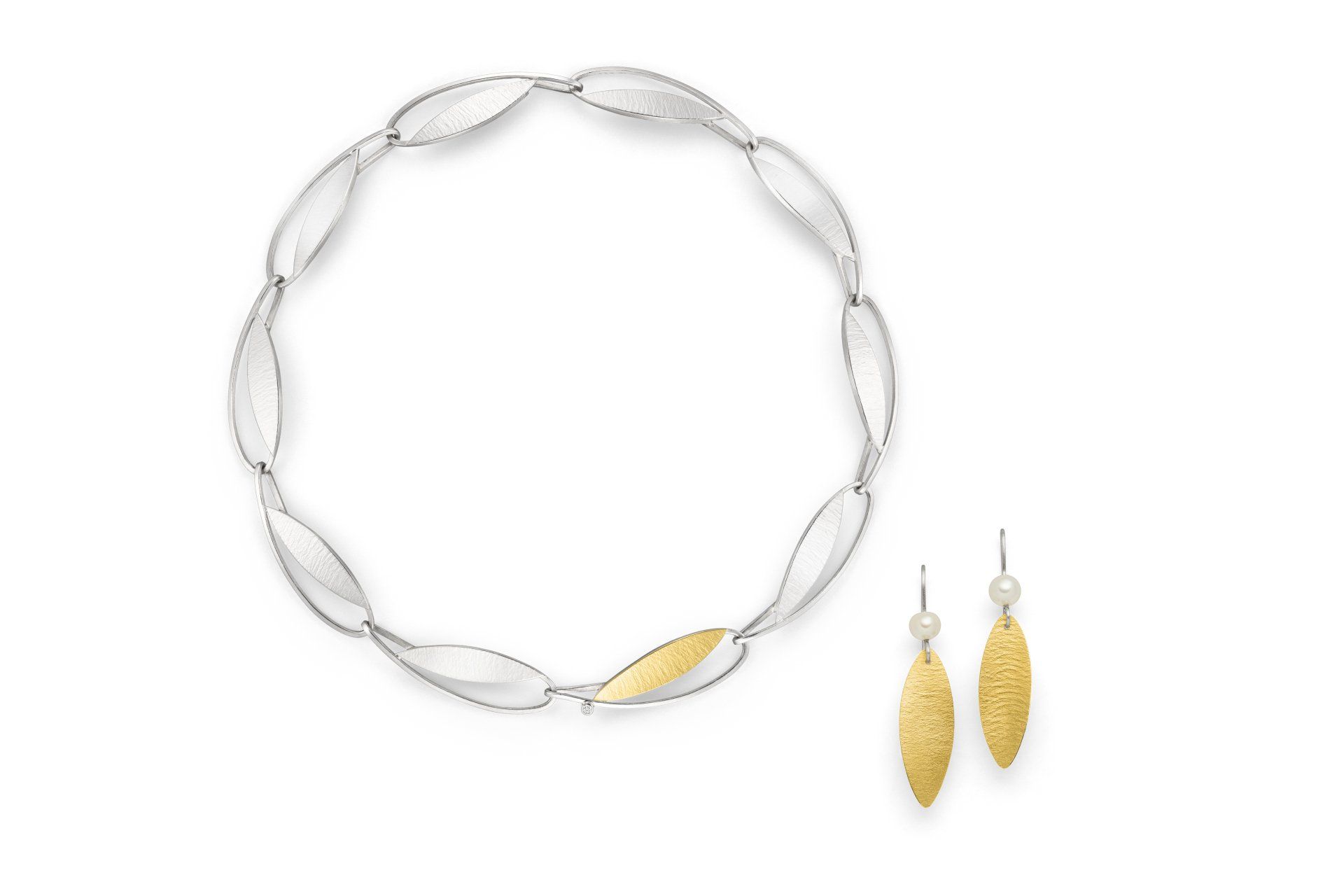 Eine silberne und goldene Halskette und Ohrringe auf weißem Hintergrund