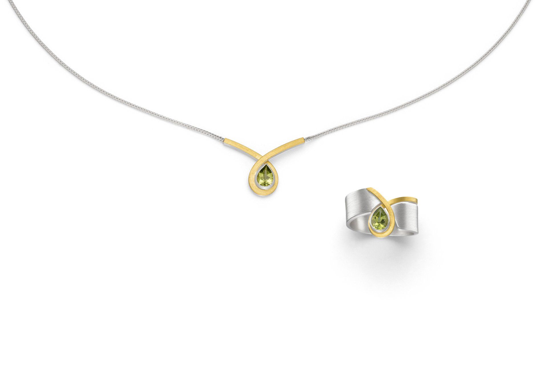 Eine Halskette und ein Ring mit einem grünen Stein auf weißem Hintergrund.