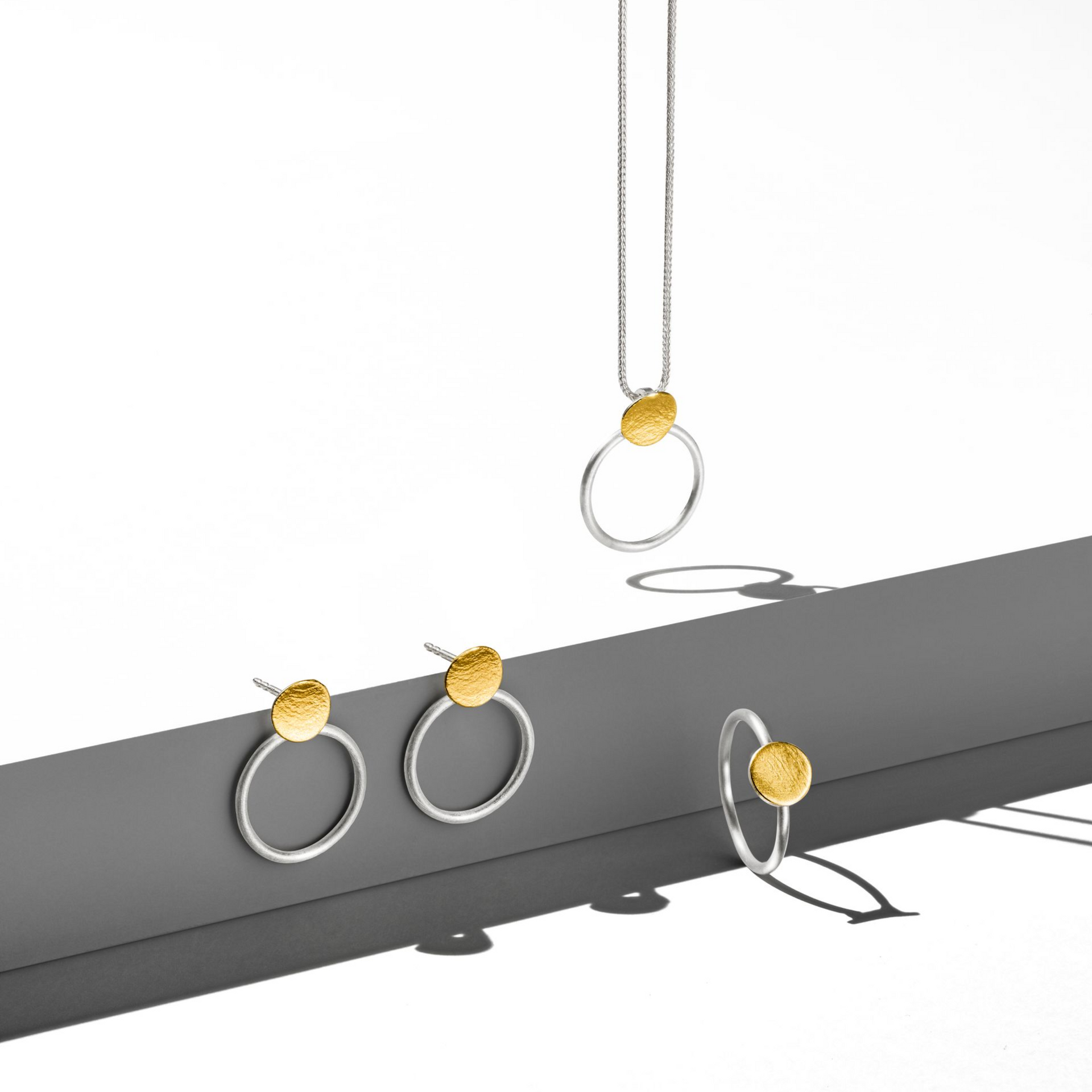 Eine Halskette, ein Armband und Ohrringe auf weißem Hintergrund.