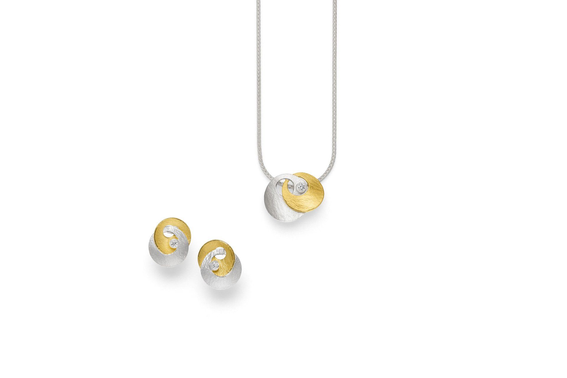 Ein Halsketten- und Ohrringset aus Silber und Gold auf weißem Hintergrund.