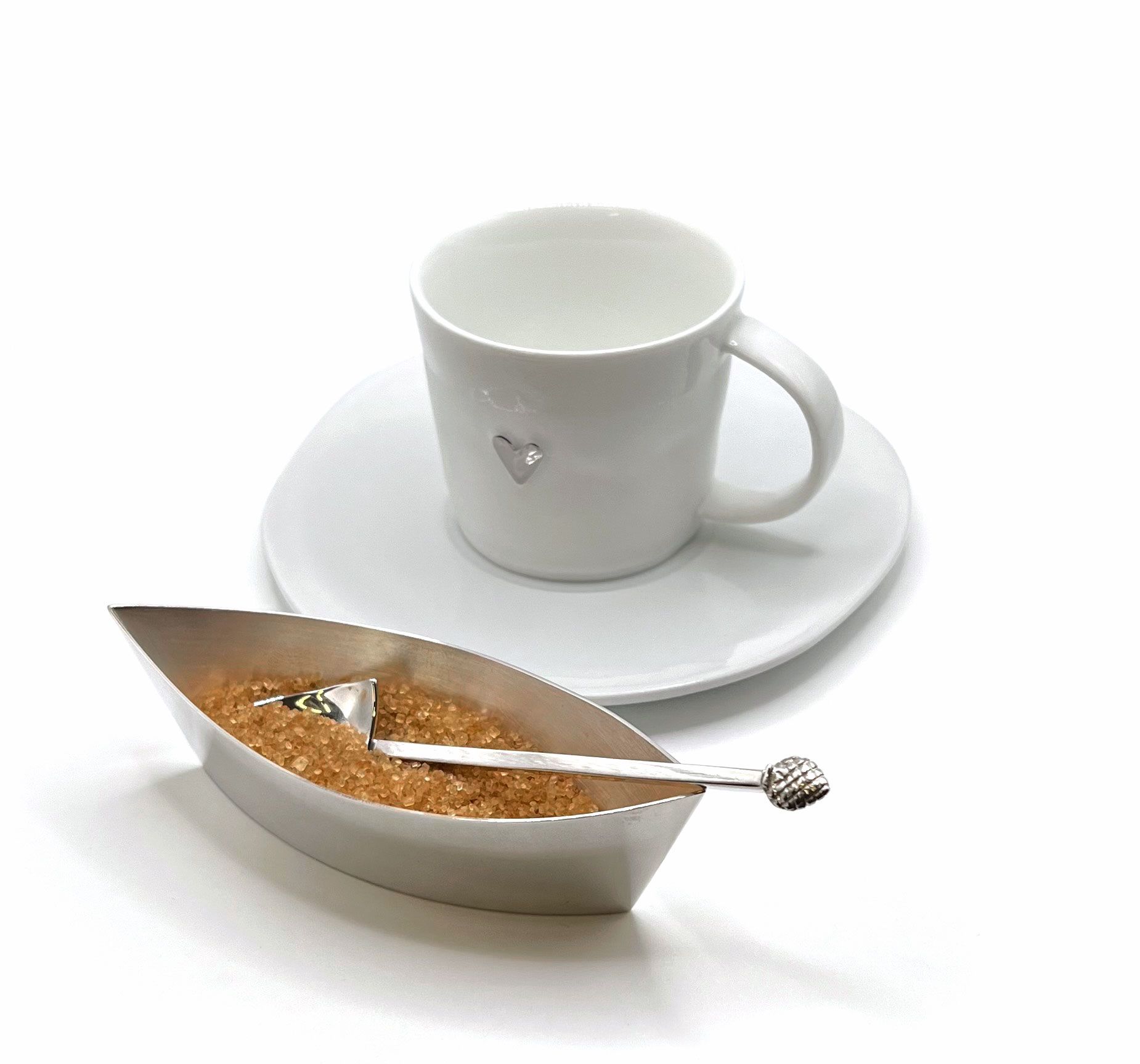 Eine Tasse Kaffee steht auf einer Untertasse neben einer Schüssel Zucker