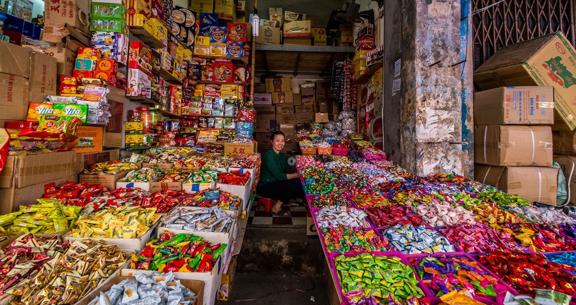 Woman surrounded by merchandises in a cluttered shop. Colorful