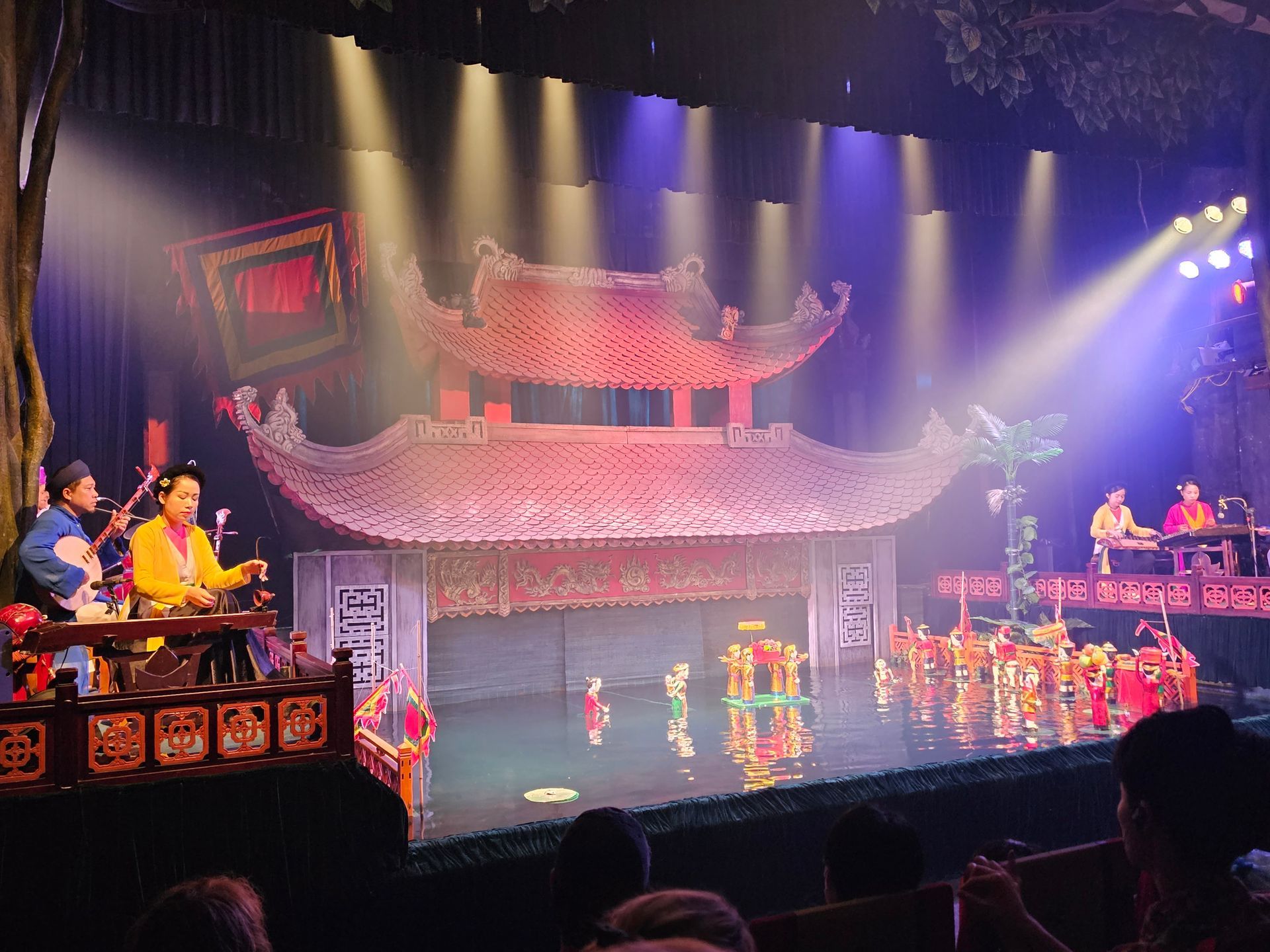 Puppet show in Hanoi, Vietnam, with musicians and colorful puppets performing on the stage.