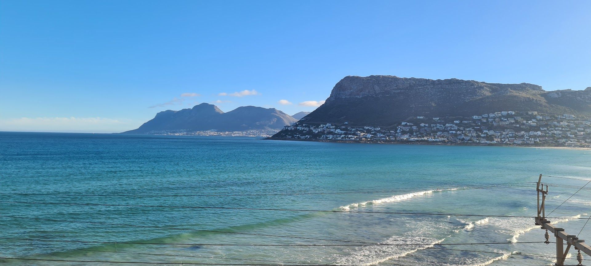 Blue ocean with distant mountains and a clear blue sky.