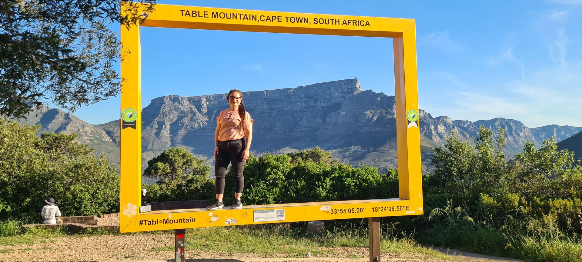 Woman stands inside a yellow frame overlooking Table Mountain, Cape Town, South Africa.