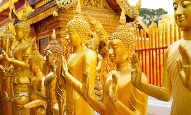Golden Buddha statues in a row, outside a temple.