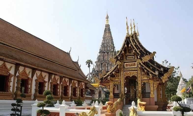 Buddhist temple complex with ornate golden structures and a tall, white pagoda.