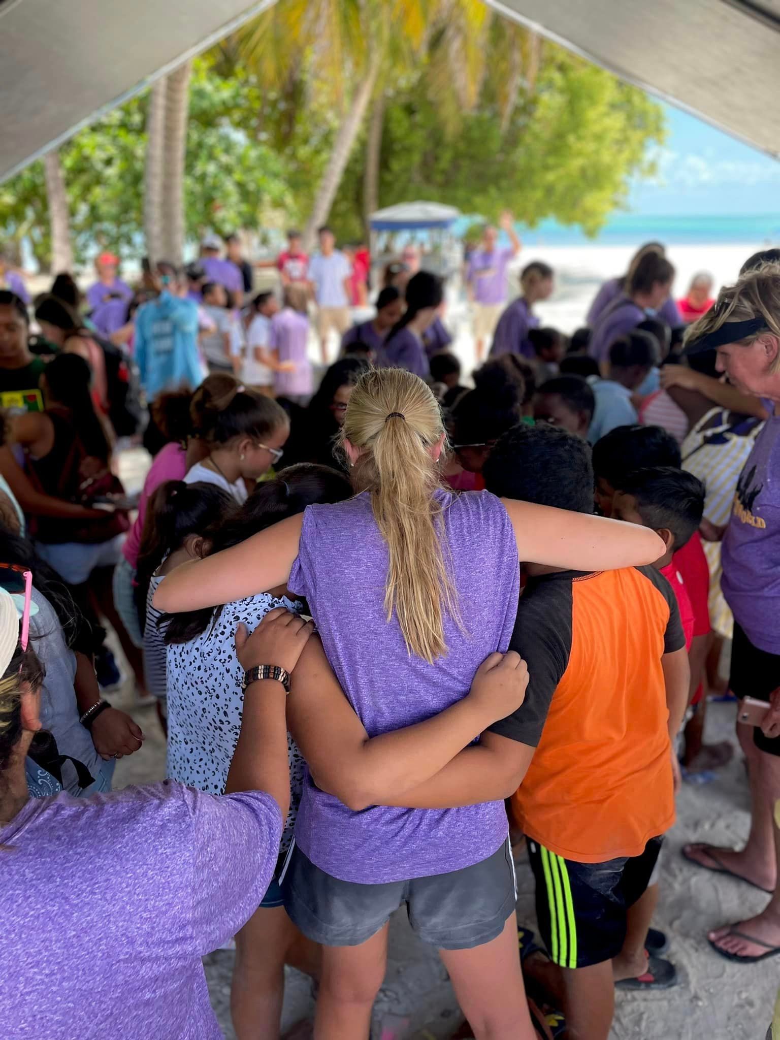 A group of people are hugging each other under a tent on a beach.