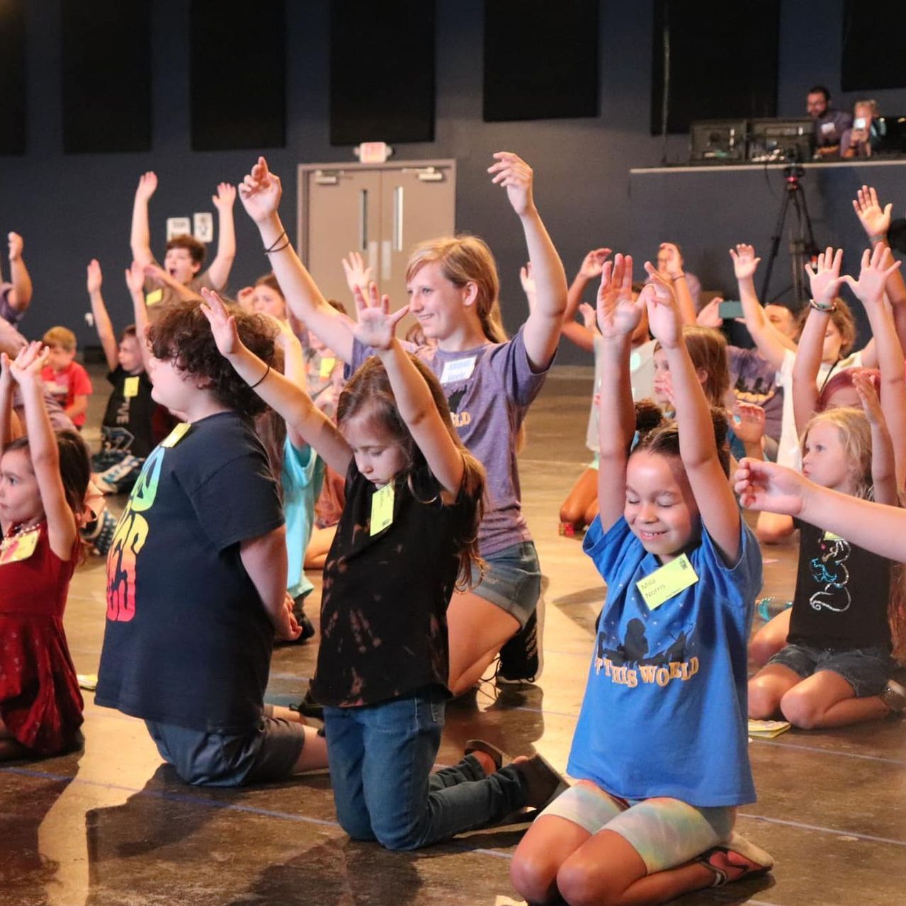 A group of children are kneeling down with their hands in the air
