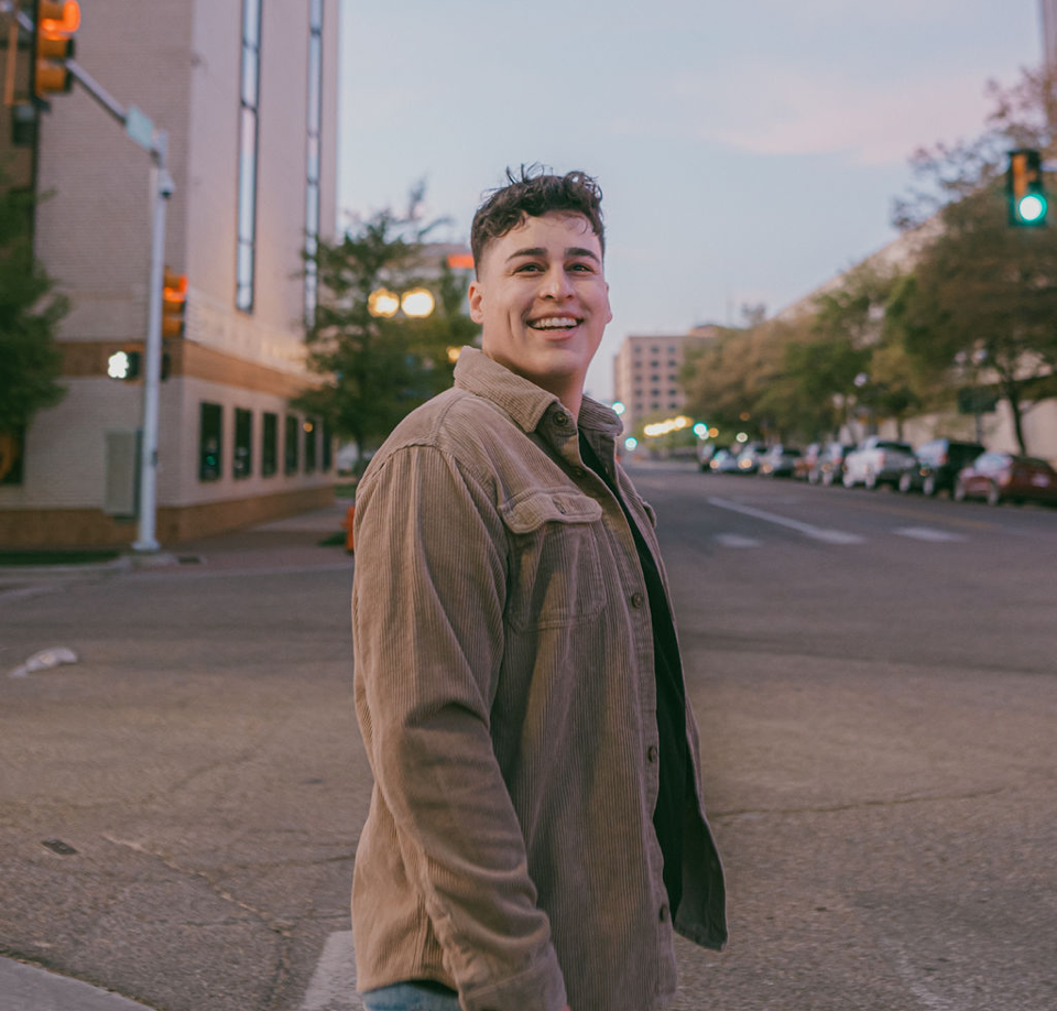 A man in a brown jacket is walking down a city street.