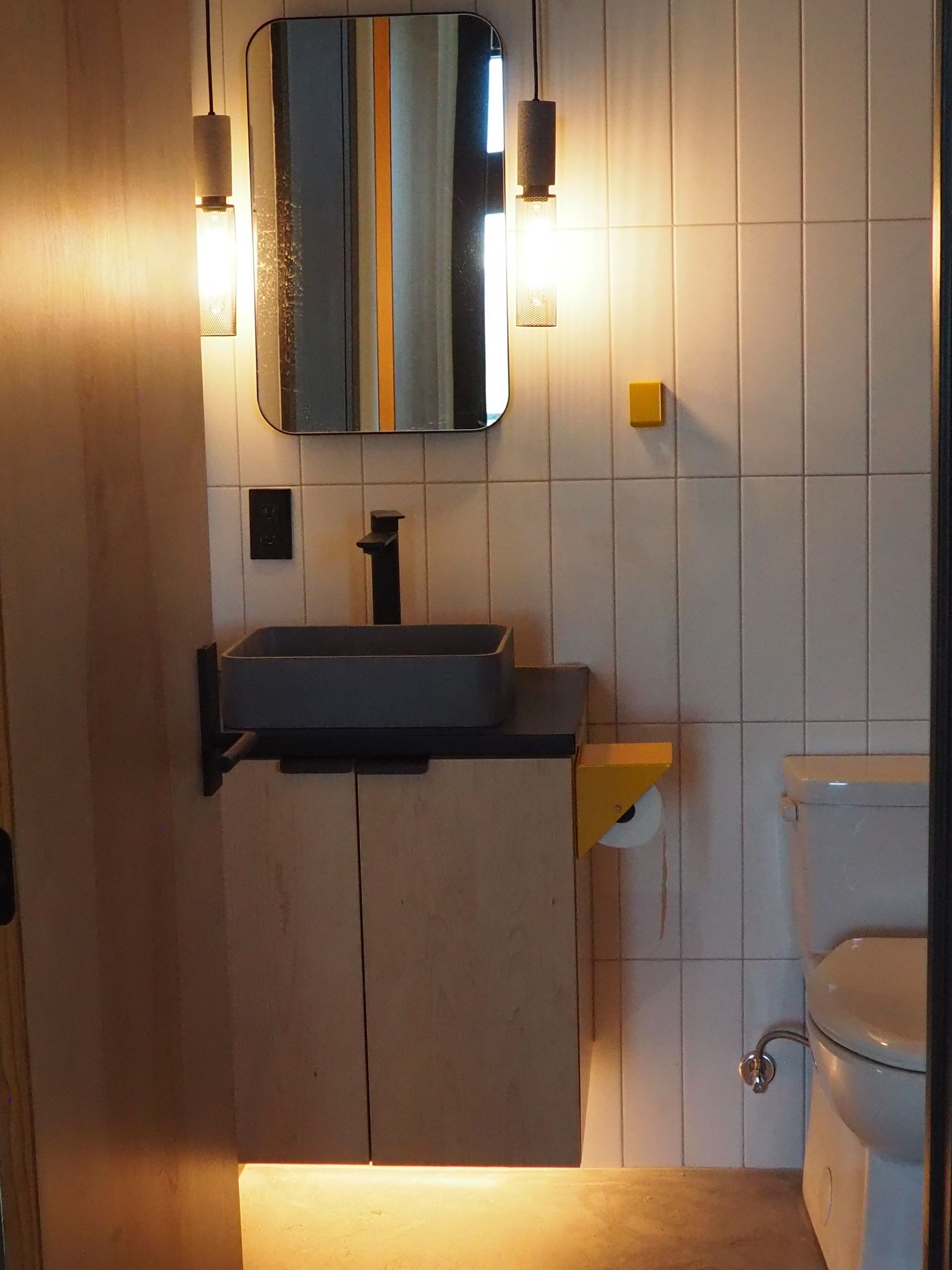 Bathroom with a floating vanity, mirror, and toilet. Light fixtures flank the mirror.