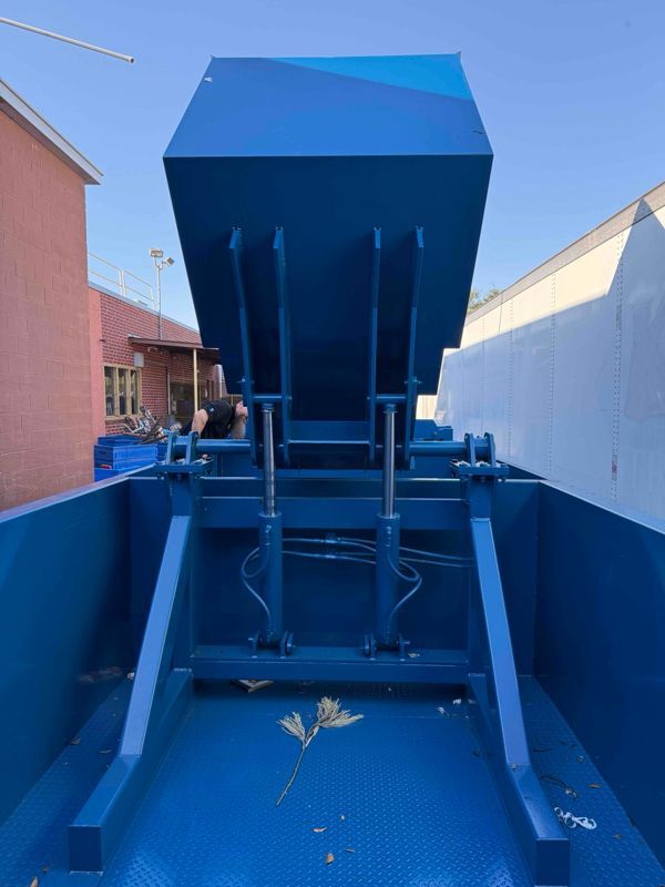 A blue dumpster is sitting in front of a building.