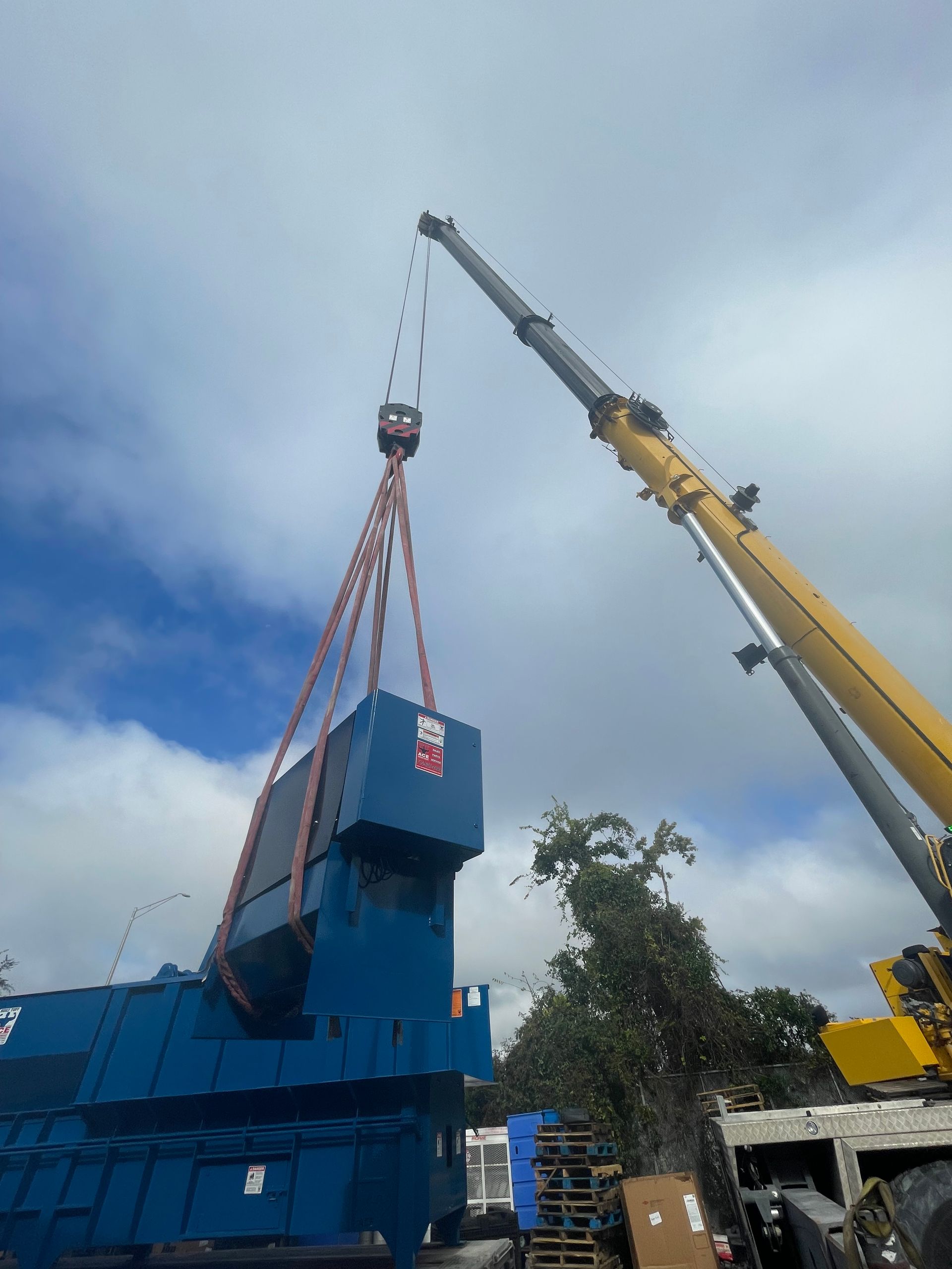 A yellow crane is lifting a large blue object