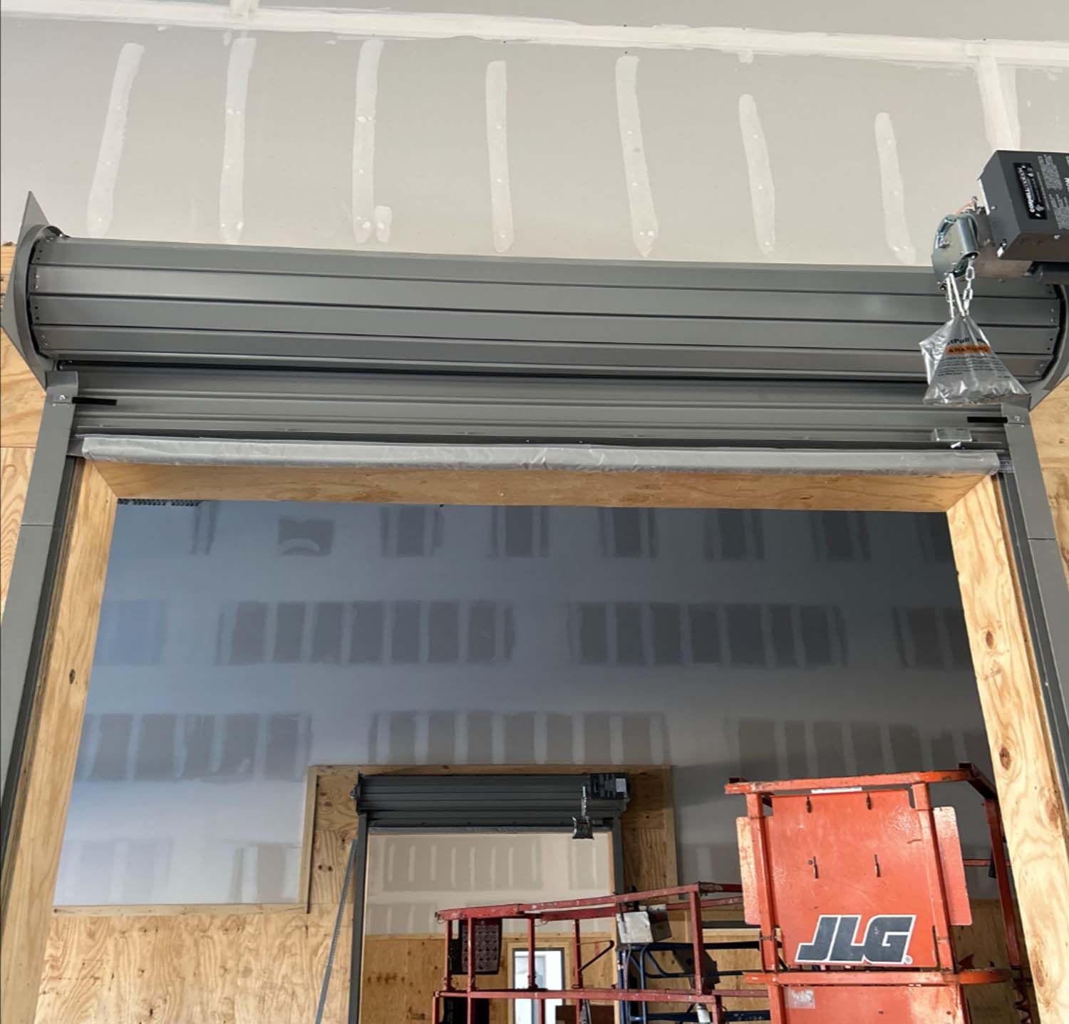 A roller door is being installed in a building under construction.