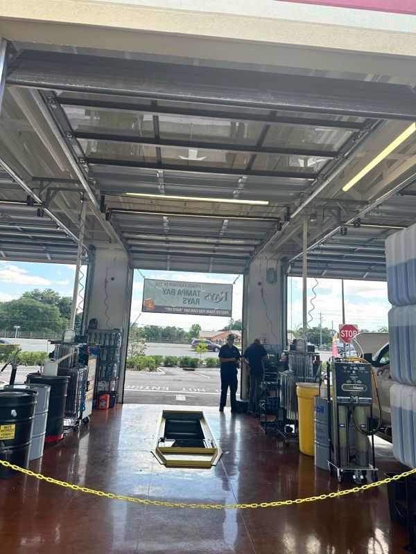 A man is standing in the doorway of a car wash.