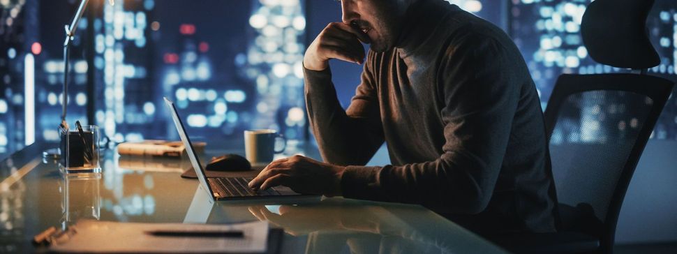 Man on computer with dark city in background