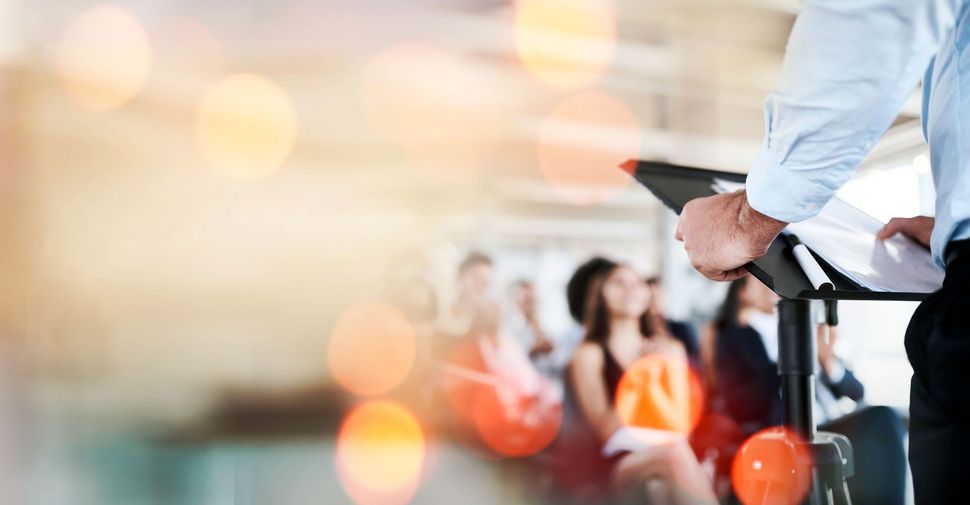 man standing at podium in front of audience