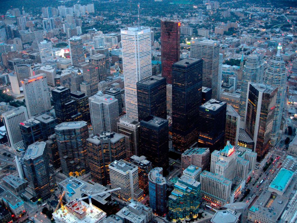 Aerial view of city skyline at dusk, featuring dense skyscrapers and illuminated office buildings