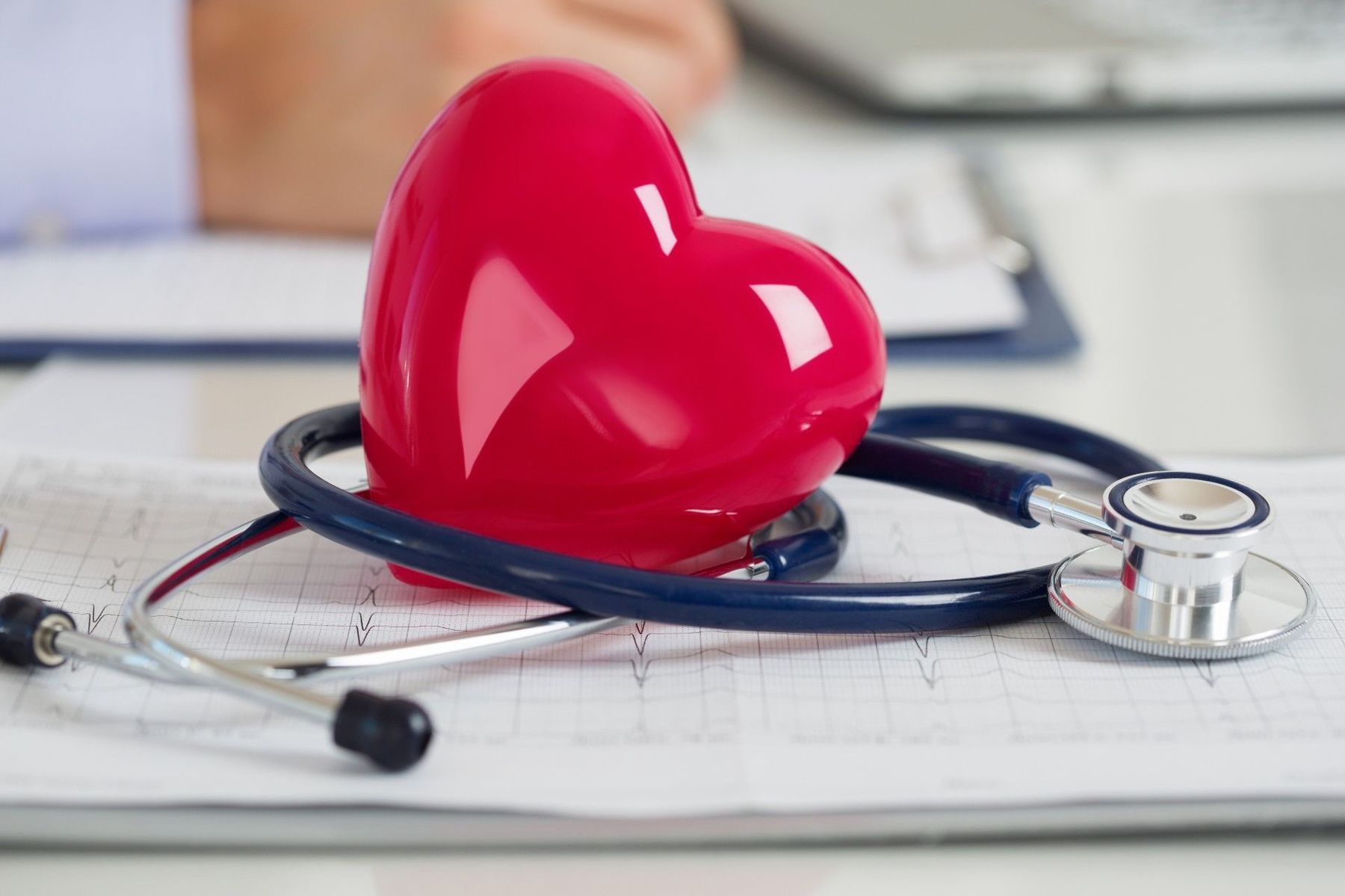 A red heart is sitting on top of a stethoscope on a table.
