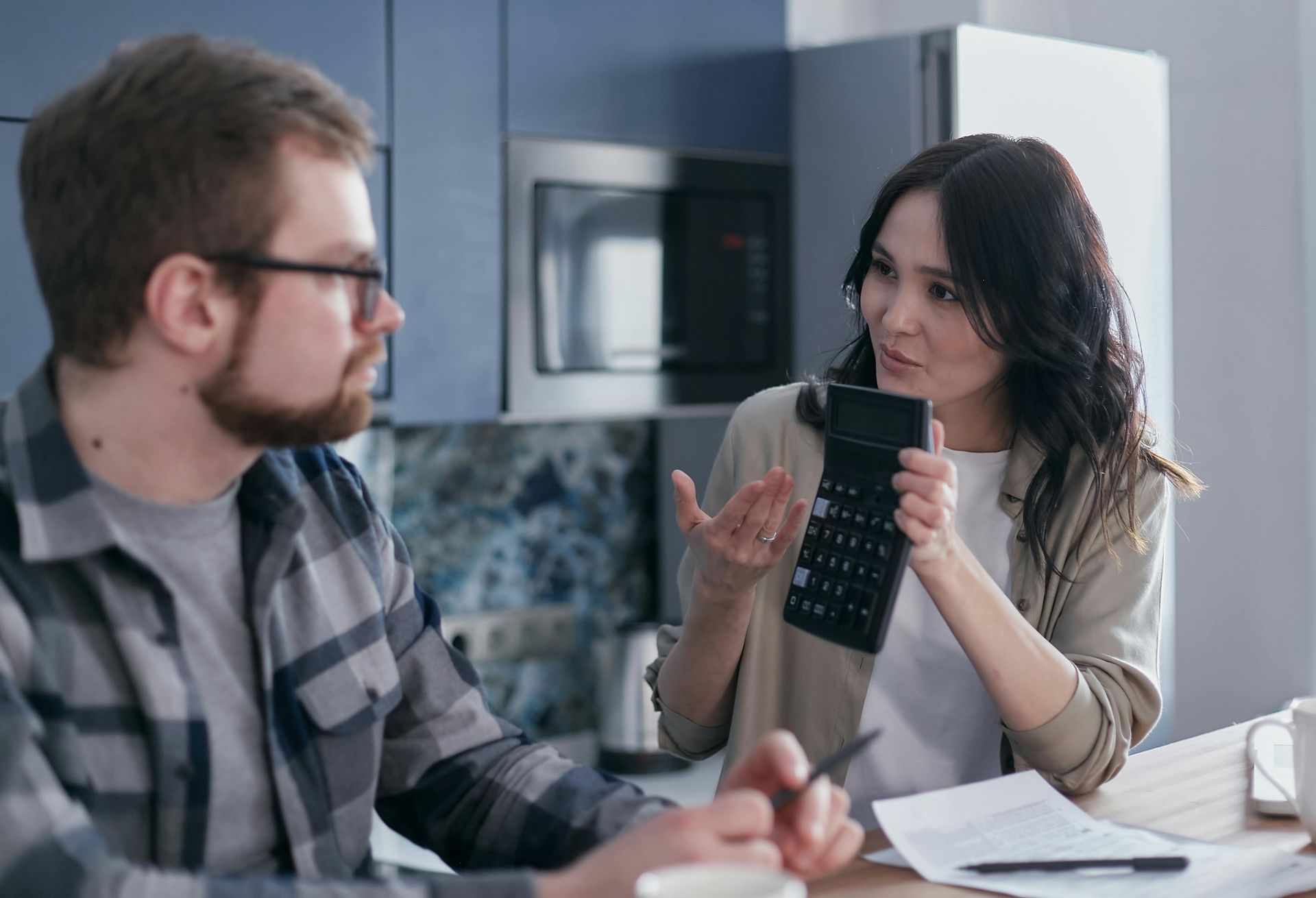 A man and a woman are sitting at a table with papers and a calculator.