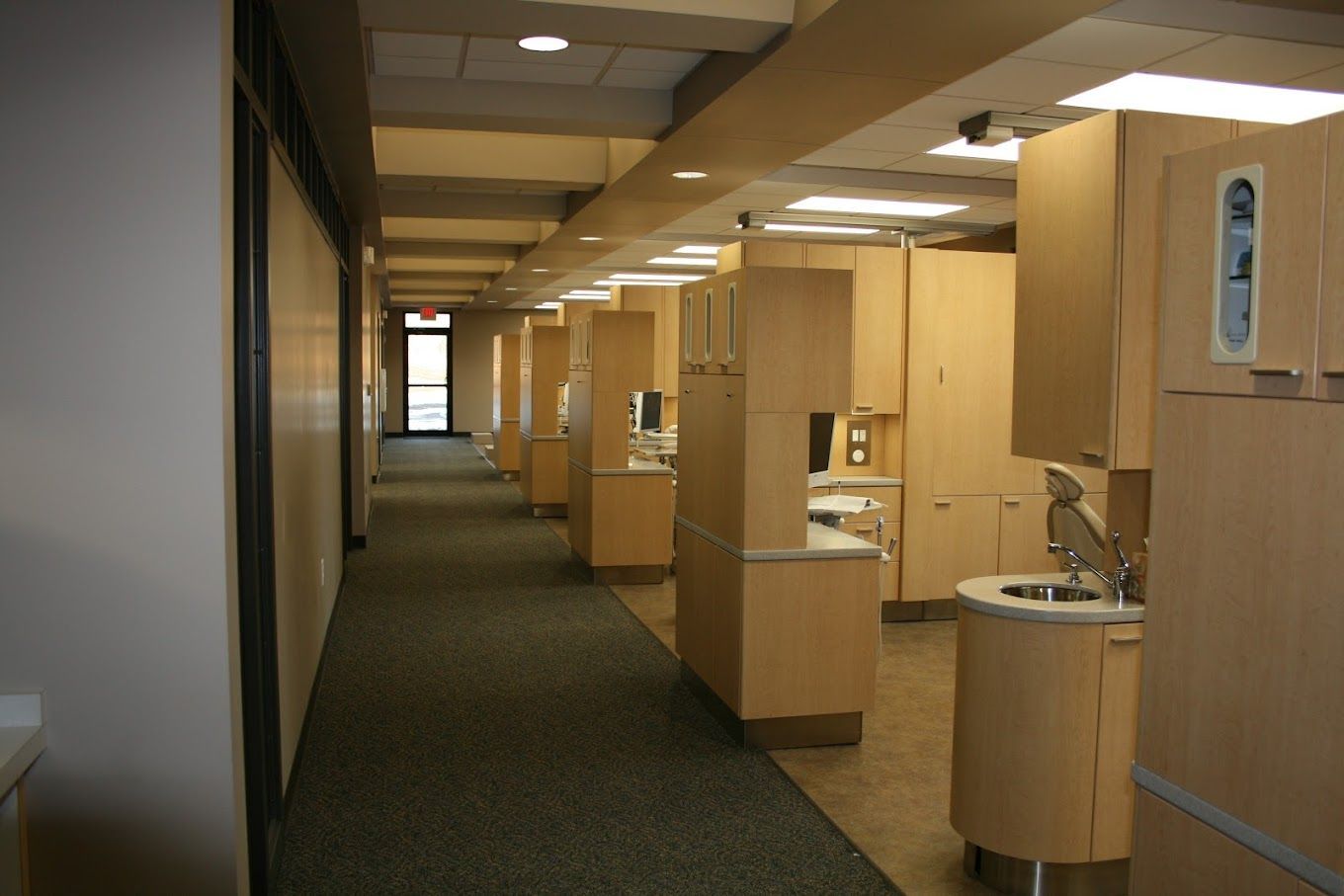 A long hallway in a dental office with cabinets and sinks