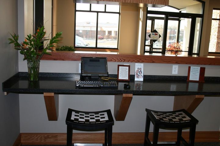 A desk with two stools and a laptop on it