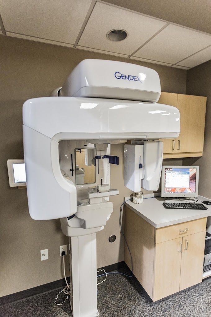 A dental office with a computer and a dental x-ray machine.