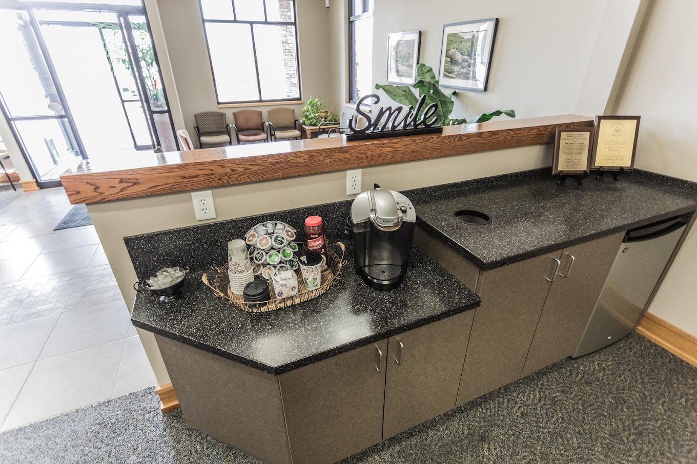 A kitchen counter with a coffee maker and a sign that says smile.