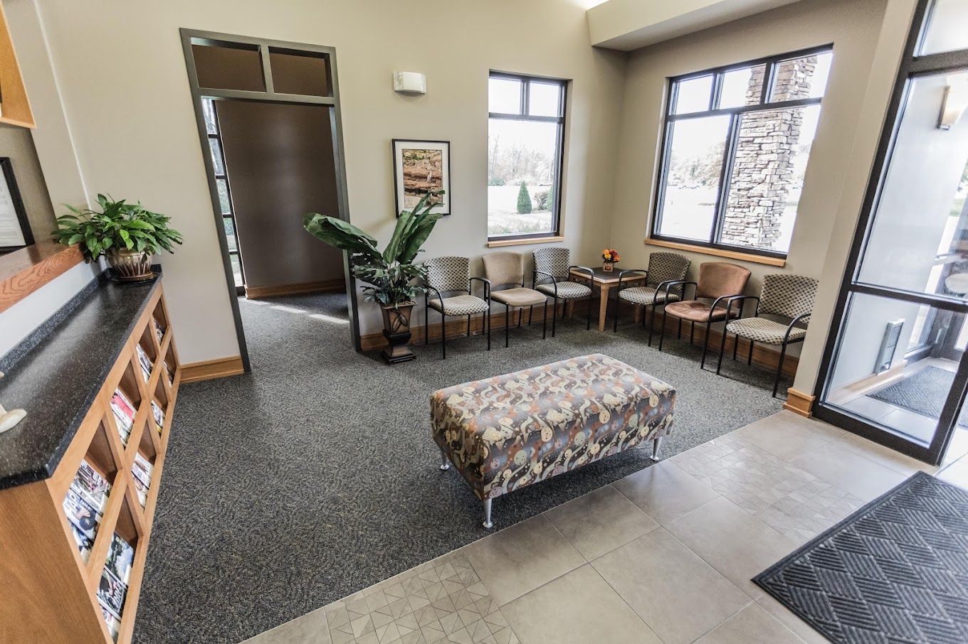 A waiting room with a bench and chairs in a dental office.