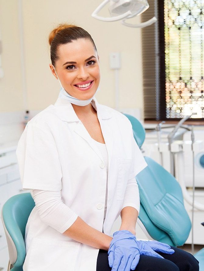 A female dentist is smiling while sitting in a dental chair.