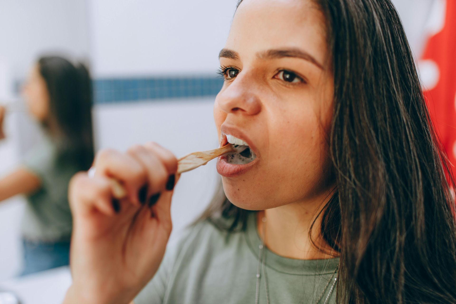 A woman is brushing her teeth in front of a mirror in a bathroom.