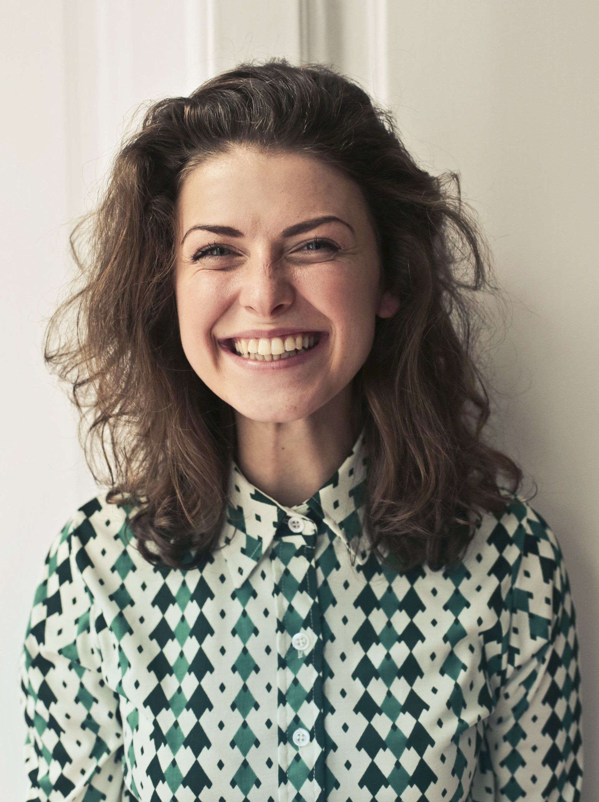 A woman wearing a green and white shirt is smiling