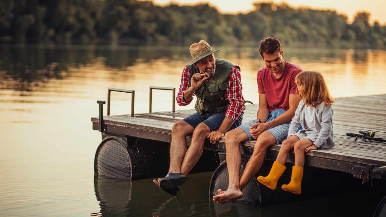 A group of people are sitting on a dock near a lake.