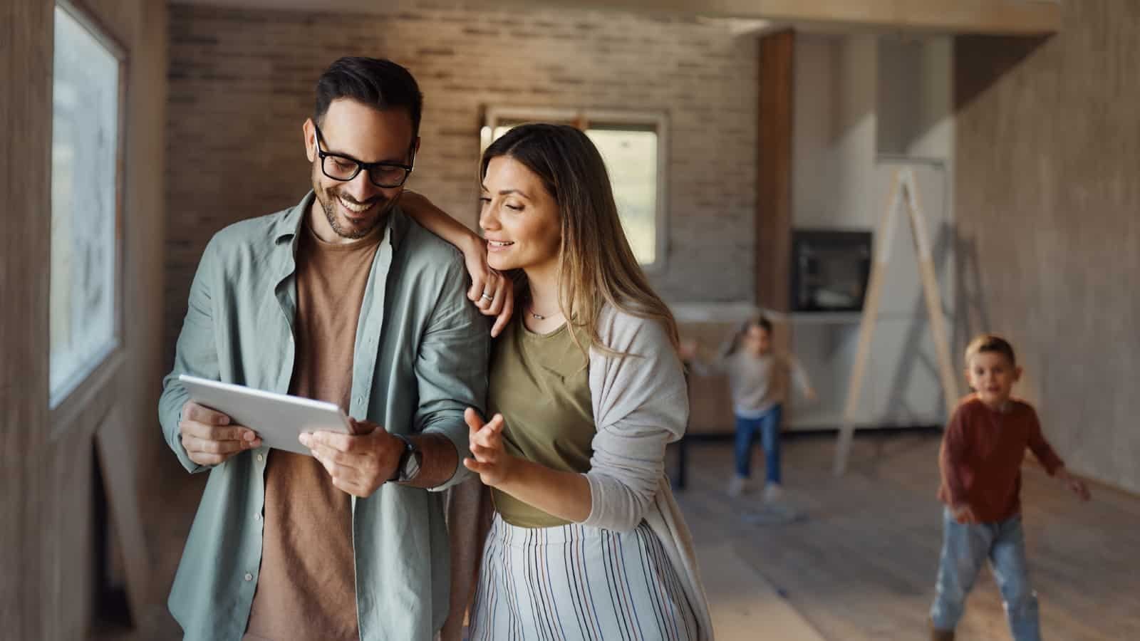 A man and woman are looking at a tablet in their new home.