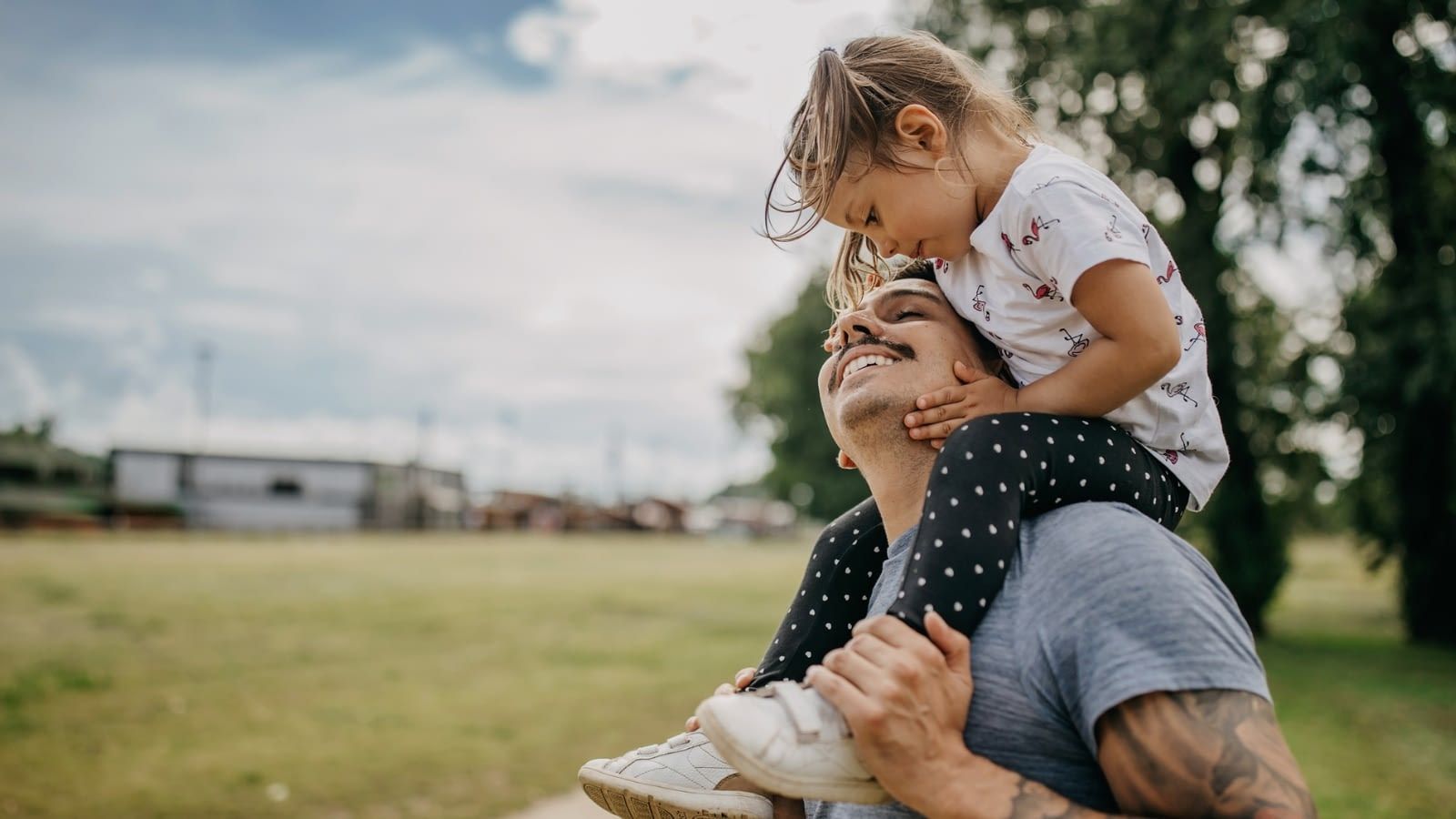 dad outside with his daughter on his shoulders