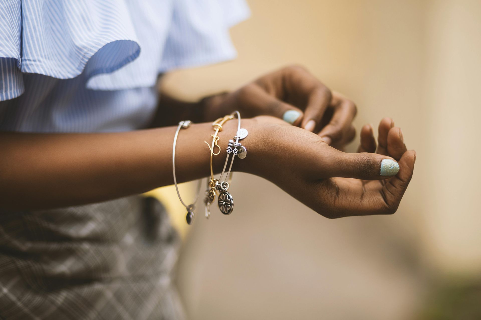 A woman is wearing a lot of bracelets on her wrist.