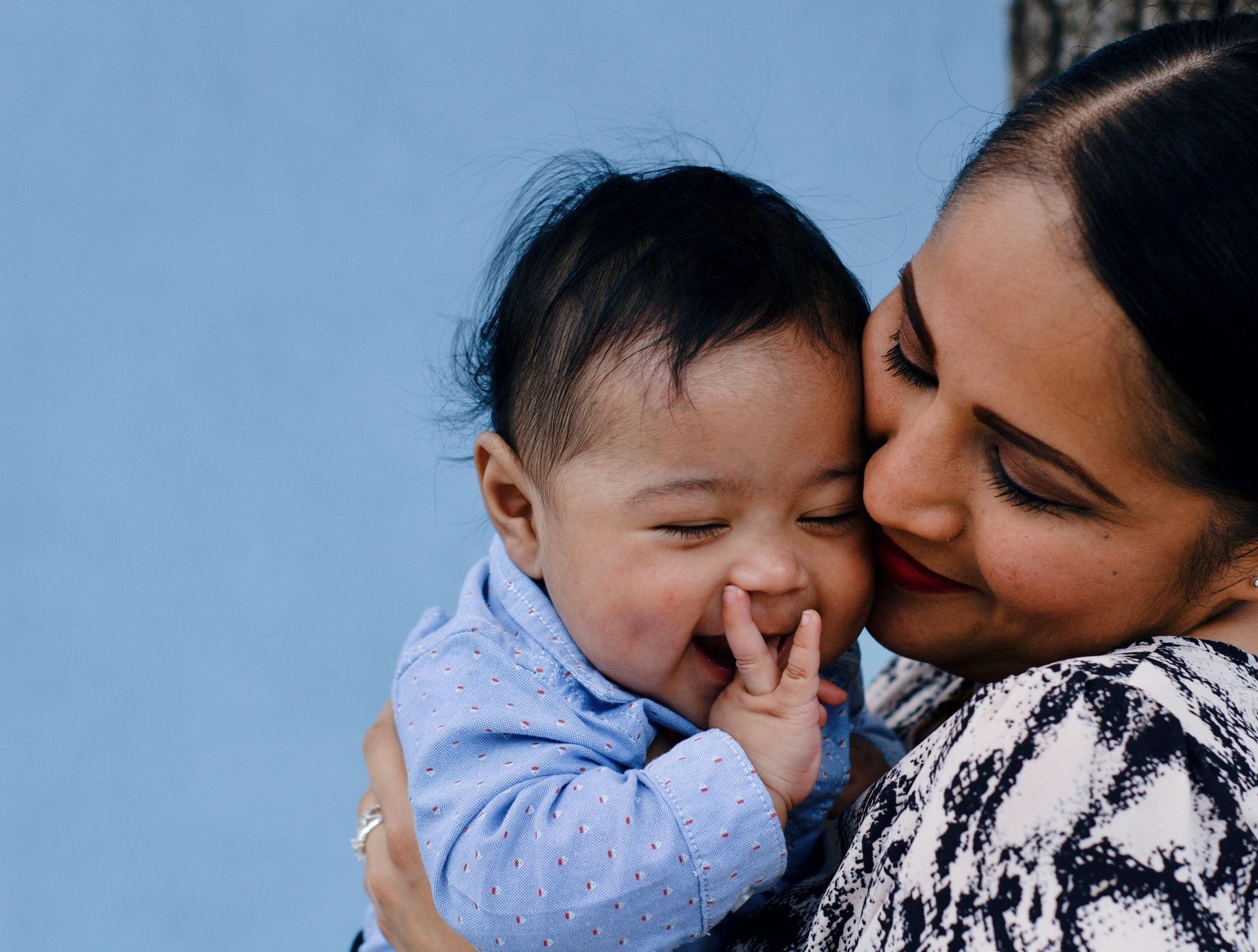 A woman is holding a baby in her arms and kissing it on the cheek.