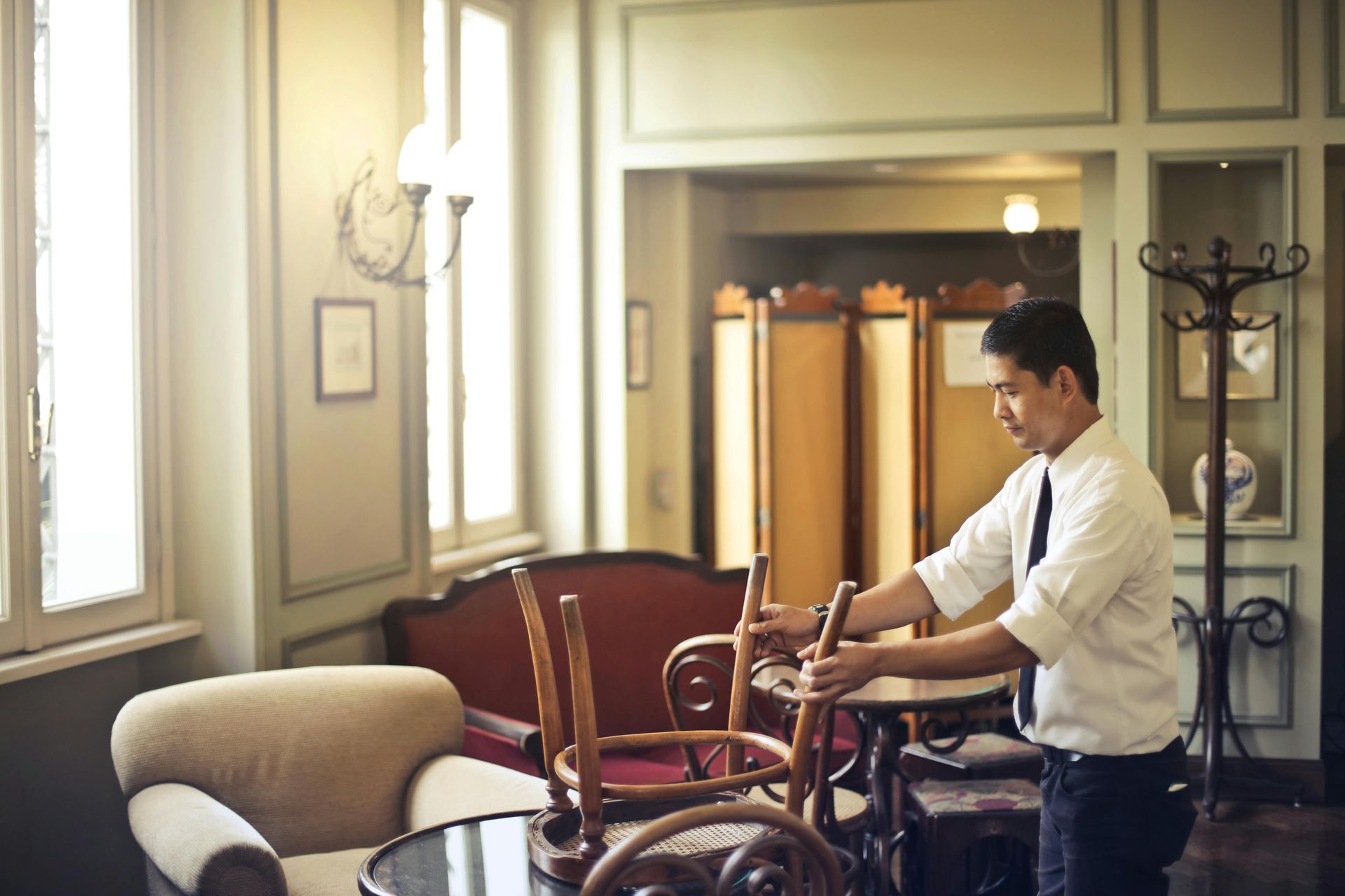 A man is putting chairs on a table in a room.