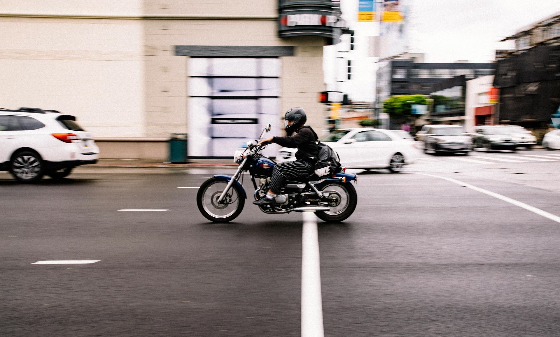 A man is riding a motorcycle down a city street.