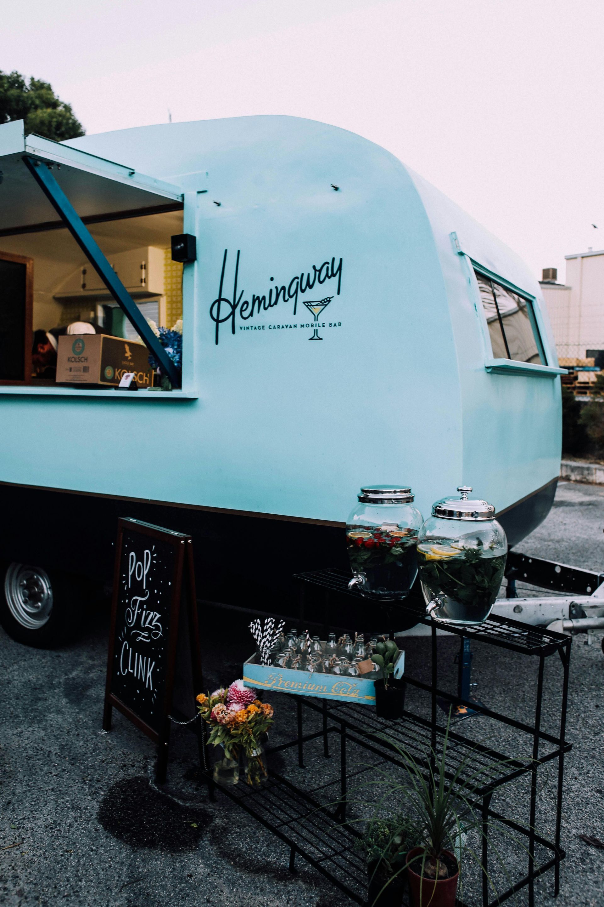 A blue food truck with the word hemingway on the side is parked in a parking lot.