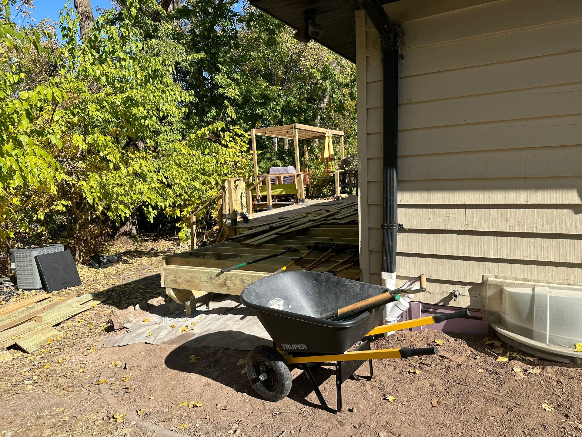 A wheelbarrow is sitting in the dirt in front of a house.