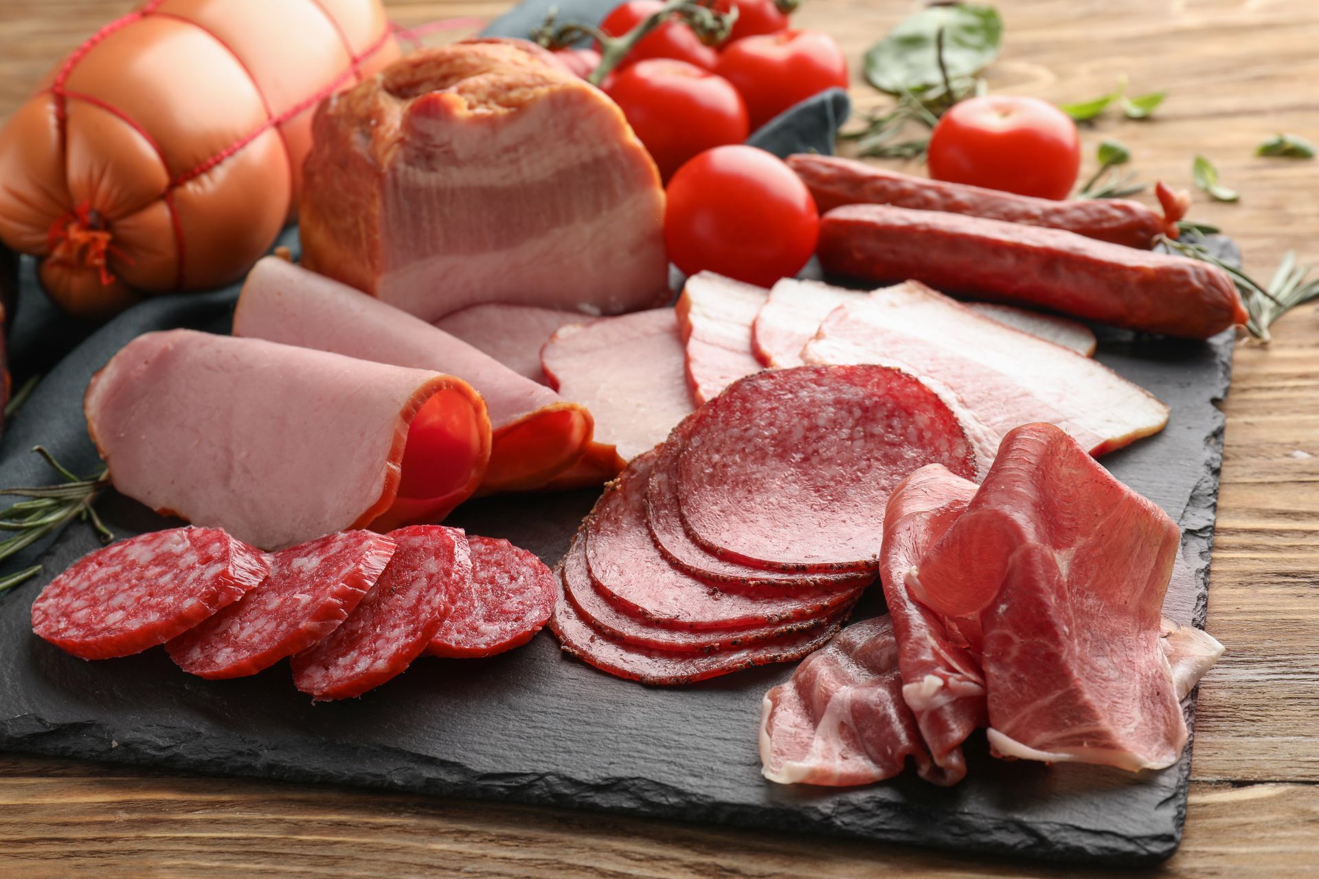 Une variété de viandes et de saucisses sur une planche à découper sur une table en bois.